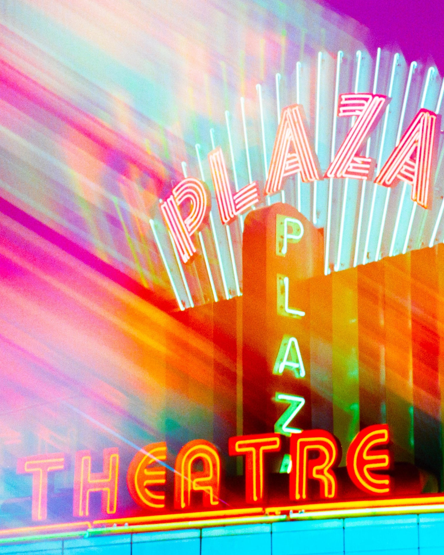 Neon sign for Plaza Theatre with vibrant colors on a colorful background